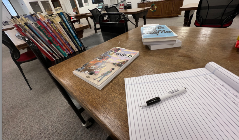 Cart of comics alongside a table and notepad inside of the Special Collections & University Archives Reading Room.